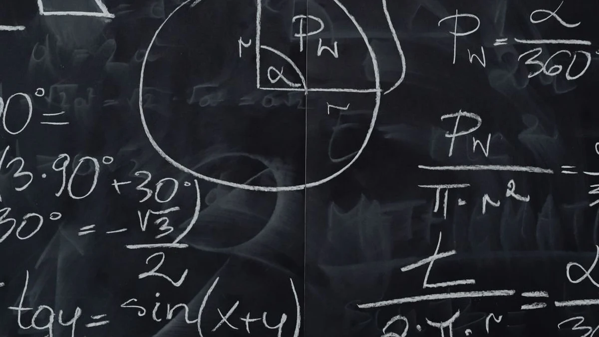 An Indian schoolboy working on maths homework at a desk at home