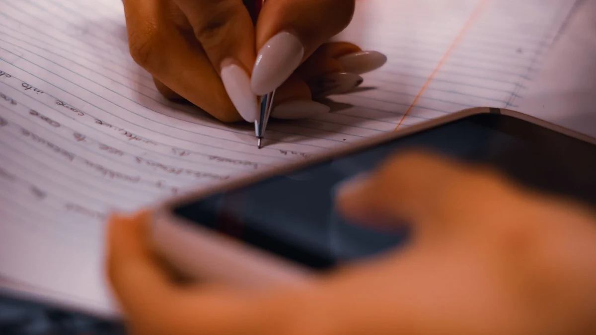 A student writing notes during a practice test, close-up of pen and paper